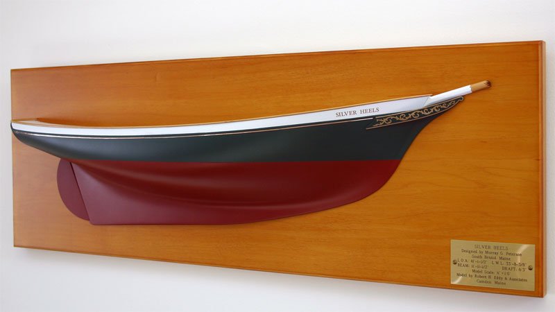 A side view of a replica model boat built by Classic Yacht Models mounted on a wall plaque, gold foil transfers are used as decals.