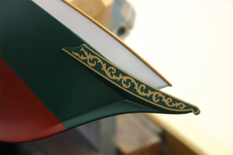 A closup photo of the bow of the model yacht showing the detail of the custom gold foil transfer they ordered.