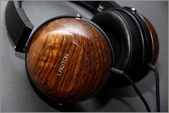 A product photo of headphones by Lawton Audio, which use a custom dry transfer on wood headphones showing their company logo.