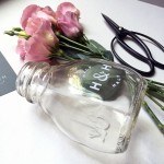 a closeup of flowers in a glass milk bottle prototype with a dry transfer of the logo on the front