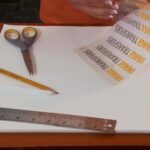 Tools used for applying custom dry transfers | Burnisher, scissors, pencil, and ruler | Custom dry transfer being peeled away from backing.