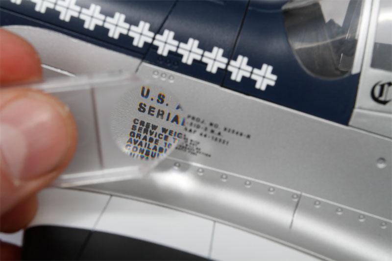 Our dry transfer model airplane decals are shown in this close up photo through a magnifying glass.