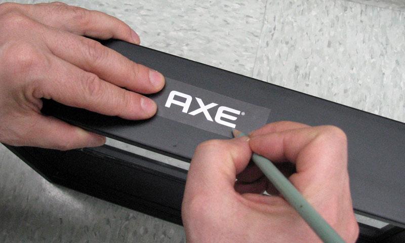 A photo of the Axe logo as a custom dry transfer being applied to the Axe Energizer product prototype.